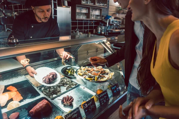 Chef experimentado eligiendo mariscos crudos del congelador para dos clientes —  Fotos de Stock