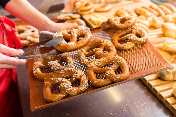 Sales lady in bakery shop selling pretzels and bread — Stock Photo, Image