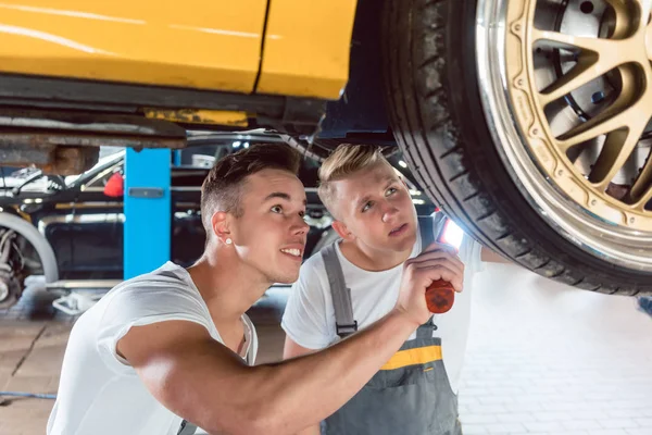 Two dedicated auto mechanics tuning a car through the modification of the rims