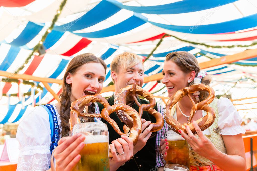 Friends eating giant pretzels and drinking in beer tent