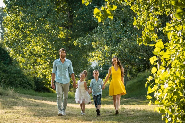 Gelukkig gezin met twee kinderen, hand in hand tijdens recreatieve wandeling — Stockfoto