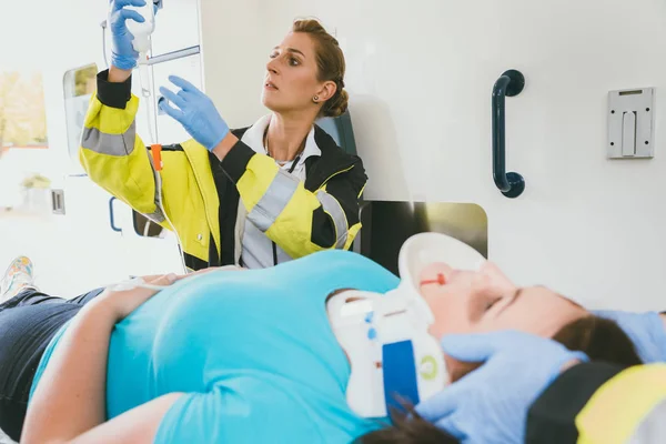 Medico che si prende cura della donna ferita con colpo di frusta in ambulanza — Foto Stock