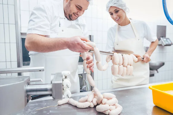 Equipo de carniceros llenando salchichas en la industria cárnica —  Fotos de Stock