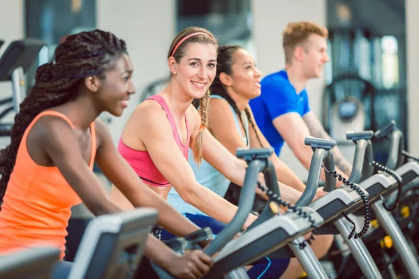 Vista lateral de una hermosa mujer sonriendo mientras pedalea durante la clase de spinning — Foto de Stock