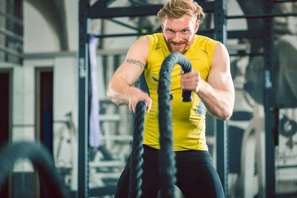 Bodybuilder beau exercice avec des cordes de combat pendant l'entraînement fonctionnel — Photo