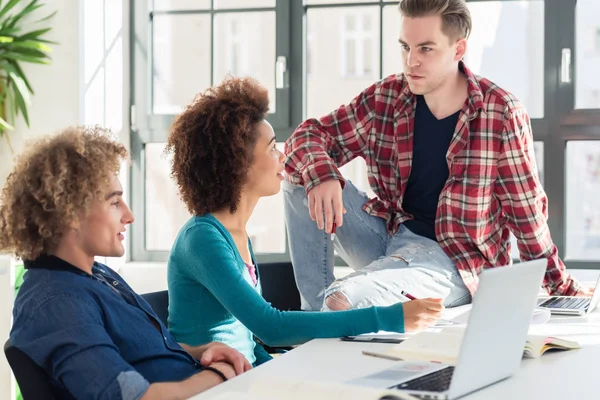 Relajado joven estudiante hablando con sus compañeros de clase durante el descanso — Foto de Stock