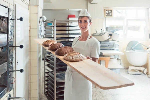 ボード上のパン屋さんでパンを提示ベイカー女性 — ストック写真