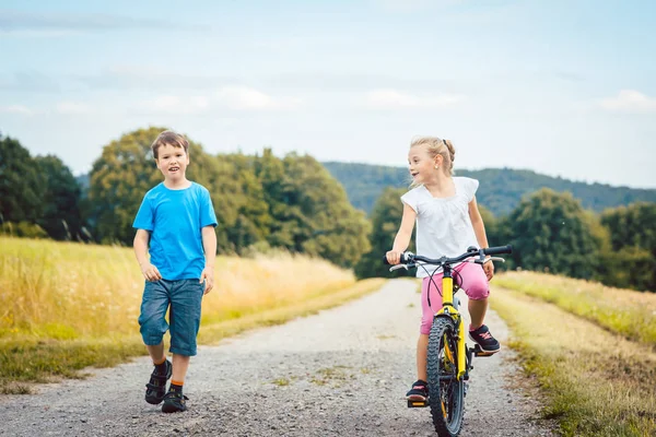 Menino e menina andando e andando de bicicleta em um caminho de sujeira — Fotografia de Stock