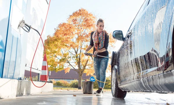 महिला स्वत: ची सेवा कार वॉशमध्ये तिचे वाहन स्वच्छ करते — स्टॉक फोटो, इमेज