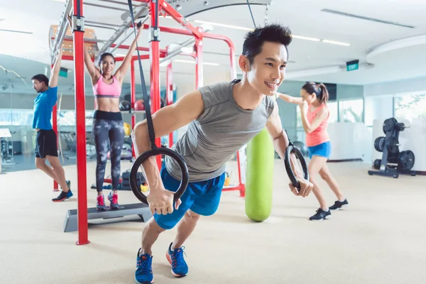 Fit young man exercising with gymnastic rings in a trendy fitness — Stock Photo, Image