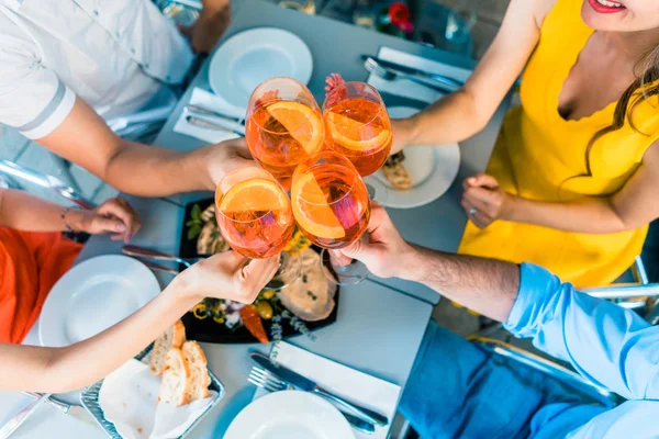 Vista en ángulo alto de las manos de cuatro amigos brindando durante el almuerzo — Foto de Stock