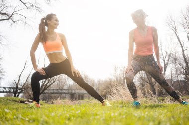 Anne ve kızı jimnastik yapıyor çayır üzerinde uzanan