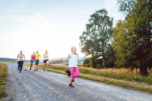 Playful family running and playing on a path in summer landscape — Stock Photo, Image
