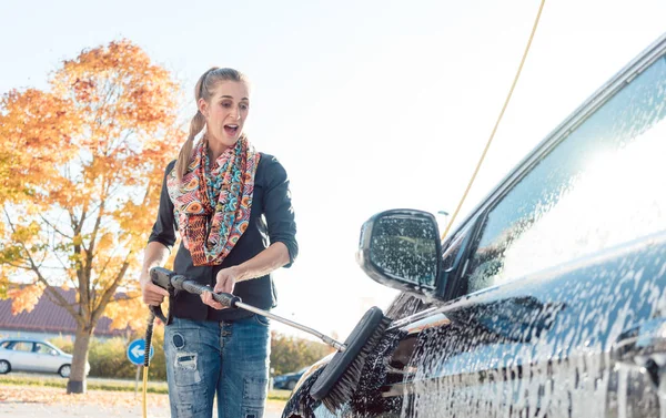 Mujer limpiando su vehículo en auto-servicio de lavado de coches — Foto de Stock