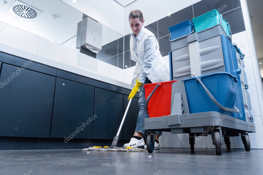 Cleaning lady mopping the floor in restroom