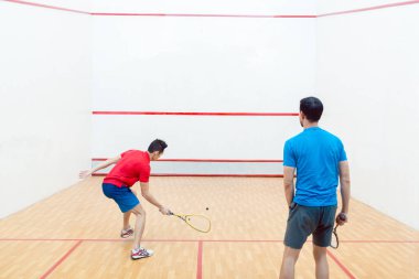 İki rekabetçi genç adamın squash oyun oynarken arka görünüm