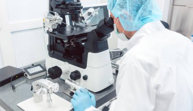Doktor ya da bilim adamı mikroskoptan laboratuara bakıyor.