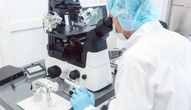 Doctor or scientist looking thru microscope in lab clipart