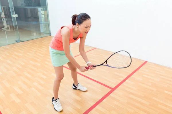 Joven jugador de squash sosteniendo la raqueta durante el juego en una cancha profesional —  Fotos de Stock