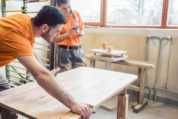 Equipa muitas vezes wo carpinteiros trabalhando em uma mesa — Fotografia de Stock