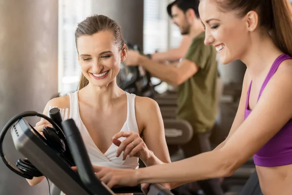 Junge Frau hilft ihrem Freund beim Einstellen des Laufbands — Stockfoto