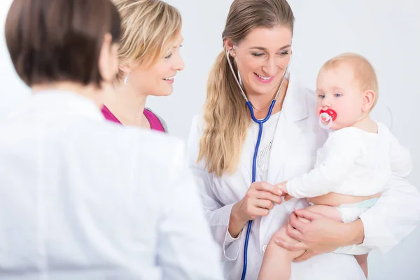 Dedicated female physician holding a cute baby girl in her arms Royalty Free Stock Images