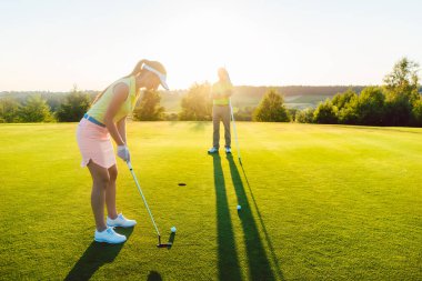 Kadın golf oyuncu topu bardağa vurmak için hazır