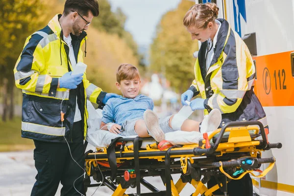 Medics putting injured boy on stretcher after accident — Stock Photo, Image