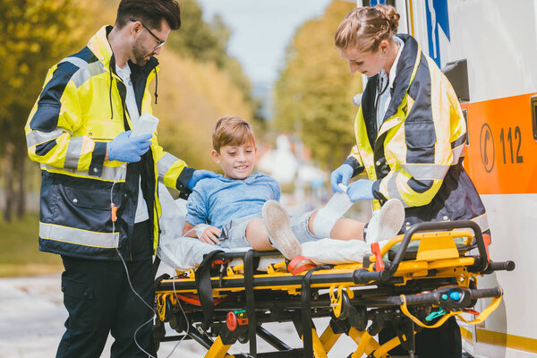 Medics putting injured boy on stretcher after accident