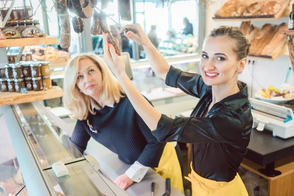 Winkelbediende vrouwen verkoop van kaas en vleeswaren in delicatessen — Stockfoto