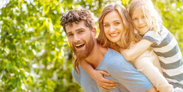 Strong man supporting his family by carrying wife and son — Stock Photo, Image