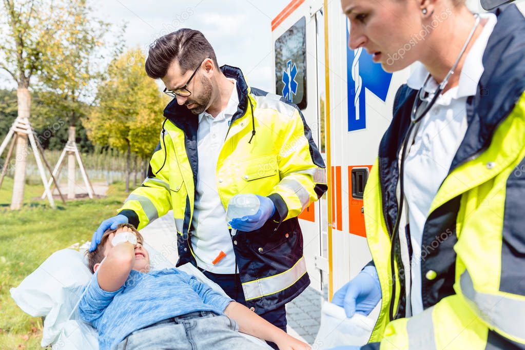 Paramedic and emergency doctor caring for injured boy 