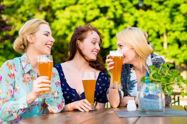 Vrienden roosteren met biertje in tuin pub — Stockfoto