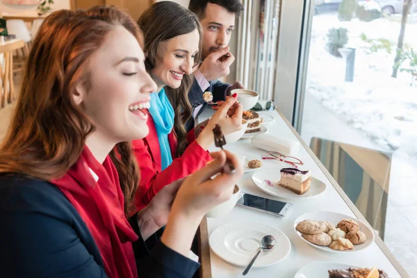 Tři kolegové s úsměvem při jídle lahodné koláče během přestávky — Stock fotografie