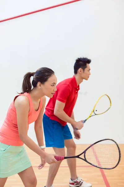 Versenyképes kínai nő tartja a teniszütő, fallabda játék közben — Stock Fotó