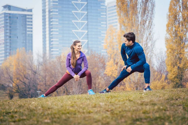 Sport couple doing warm-up exercise before starting a run