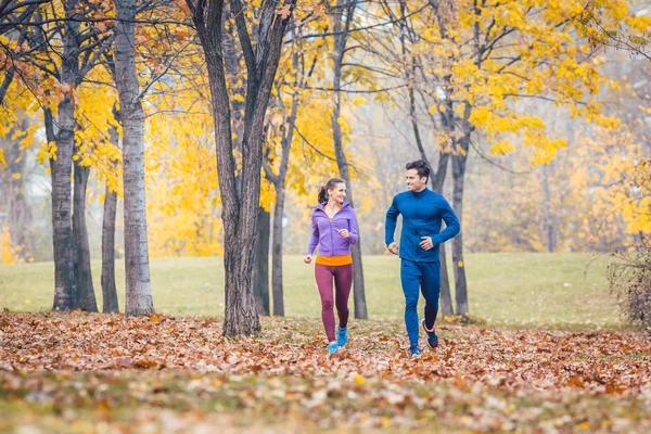 Vrouw en man loopt in herfst park voor sport — Stockfoto