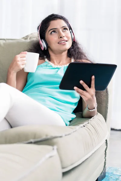 Продумана молода жінка тримає чашку кави та цифровий планшет — стокове фото