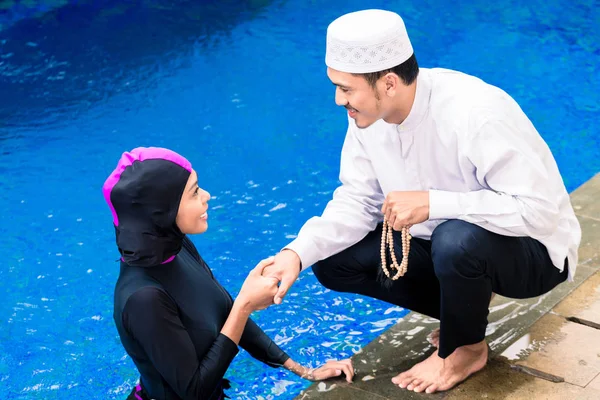 Mulher muçulmana na piscina cumprimentando seu marido — Fotografia de Stock