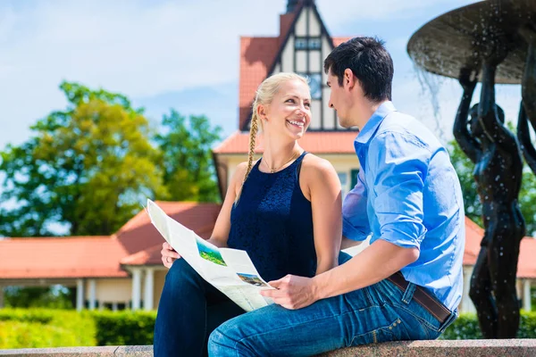 Casal olhando um para o outro segurando mapa — Fotografia de Stock