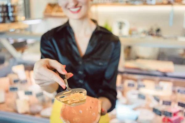 Mooie vrouw aanbieden van kaas op delicatessen teller — Stockfoto