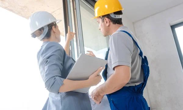 Arquitecto y trabajador de la construcción revisando ventanas en el sitio —  Fotos de Stock