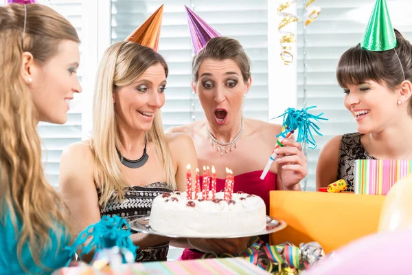 Mulher soprando velas em seu bolo de aniversário enquanto celebra — Fotografia de Stock