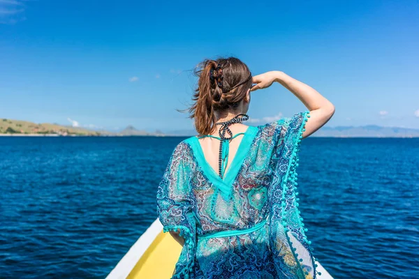 Jovem mulher olhando para o horizonte enquanto se senta em um molhe na praia — Fotografia de Stock