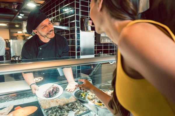 Chef experiente escolhendo frutos do mar crus do congelador para dois clientes — Fotografia de Stock