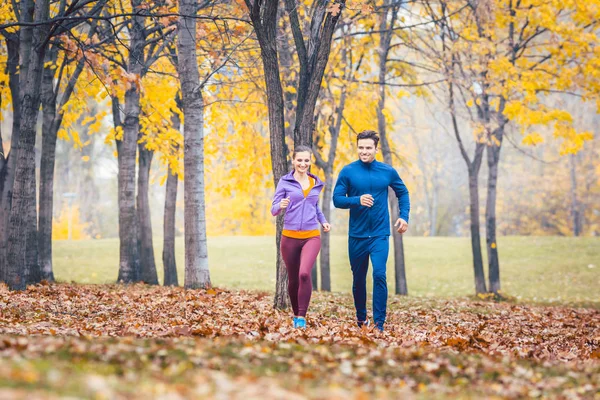 Hombre y mujer corriendo como deporte de fitness en un parque de otoño — Foto de Stock