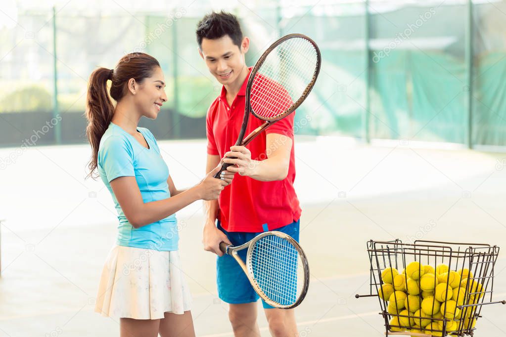Tennis instructor teaching a beginner player the correct grip