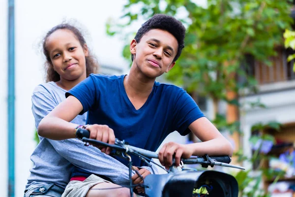 Усміхнена сестра сидить зі своїм братом їде на старому велосипеді — стокове фото