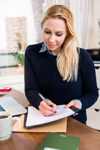 Frau am Schreibtisch schreibt auf Papier — Stockfoto