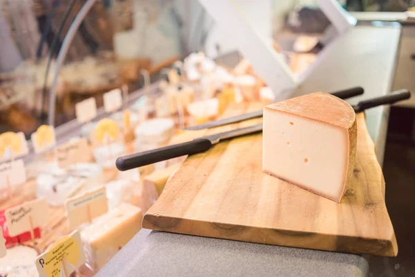 El queso a la tabla en el mostrador en la tienda de delicatessen —  Fotos de Stock